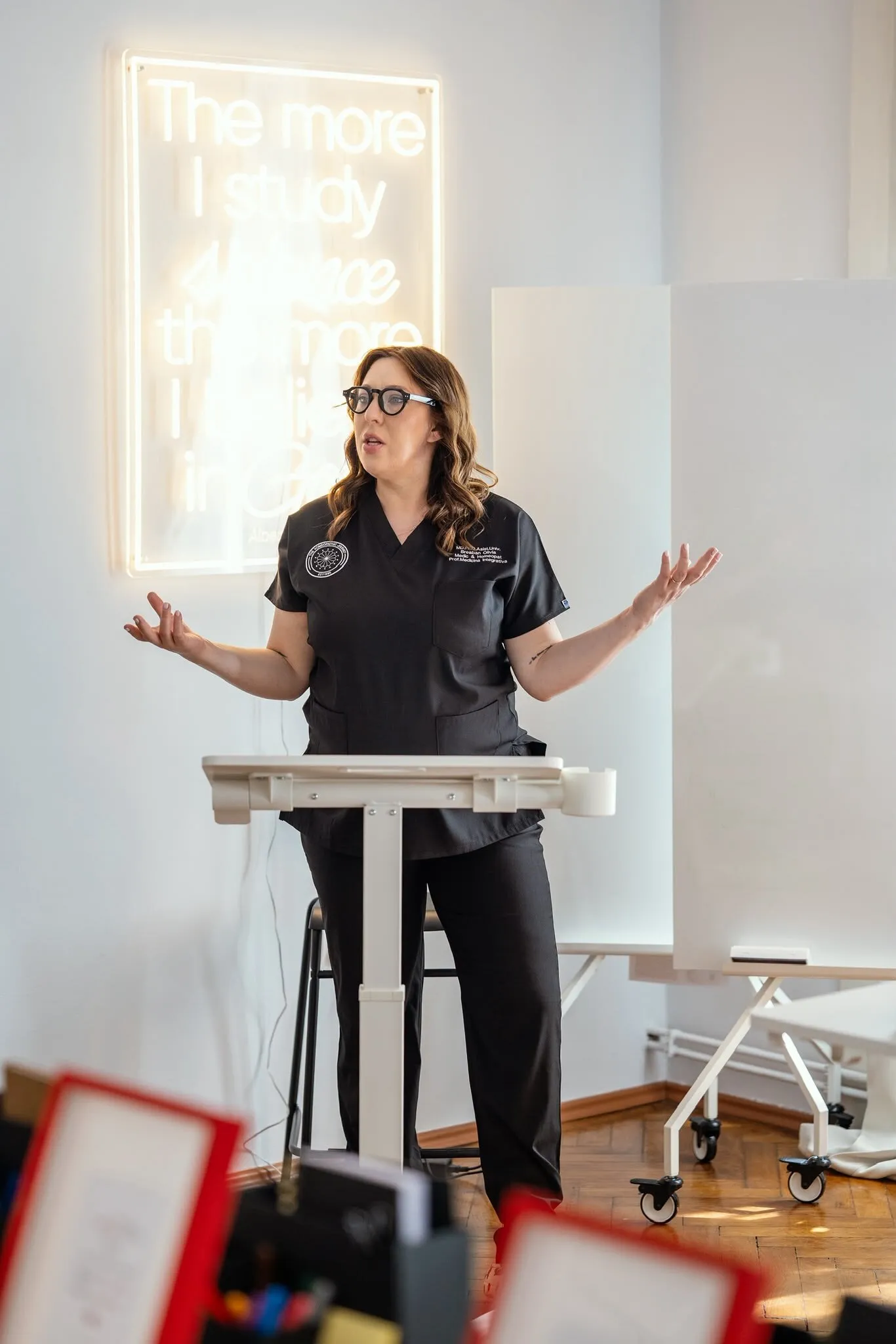 Dr. Olivia Breaban vorbind la un pupitru, în fața unui neon
